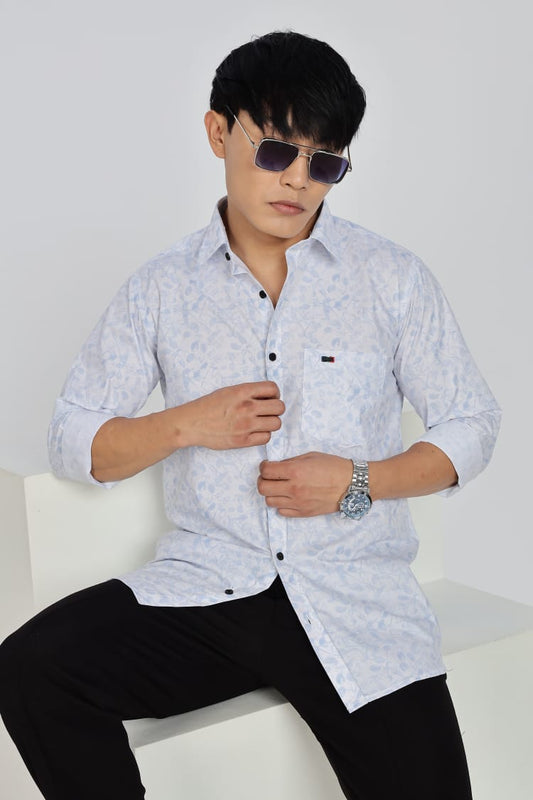 Man wearing a light-colored patterned shirt and dark pants against a white background