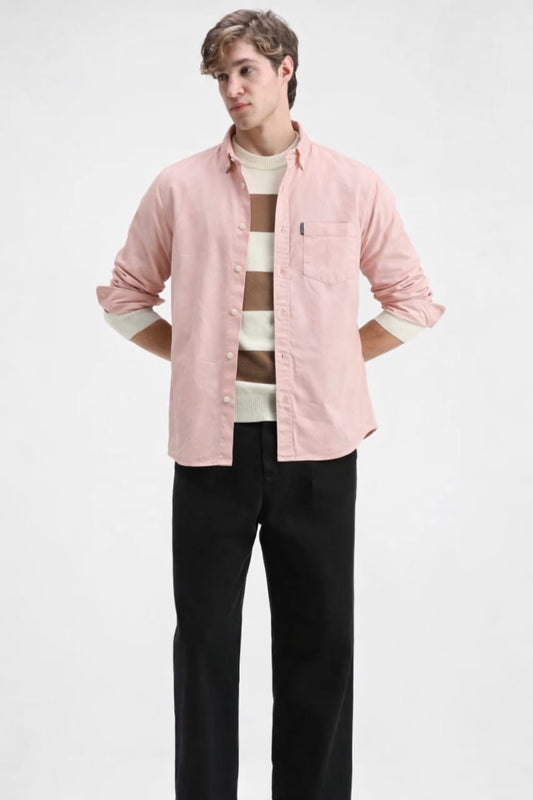 Person wearing a pink shirt with rolled-up sleeves, striped sweater, and black pants on a white background