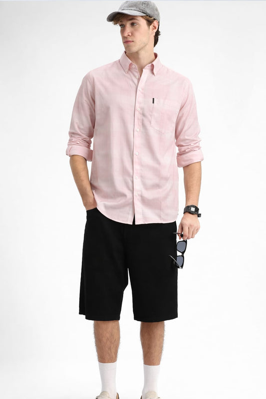 Man wearing a pink shirt, black shorts, and a cap on a white background