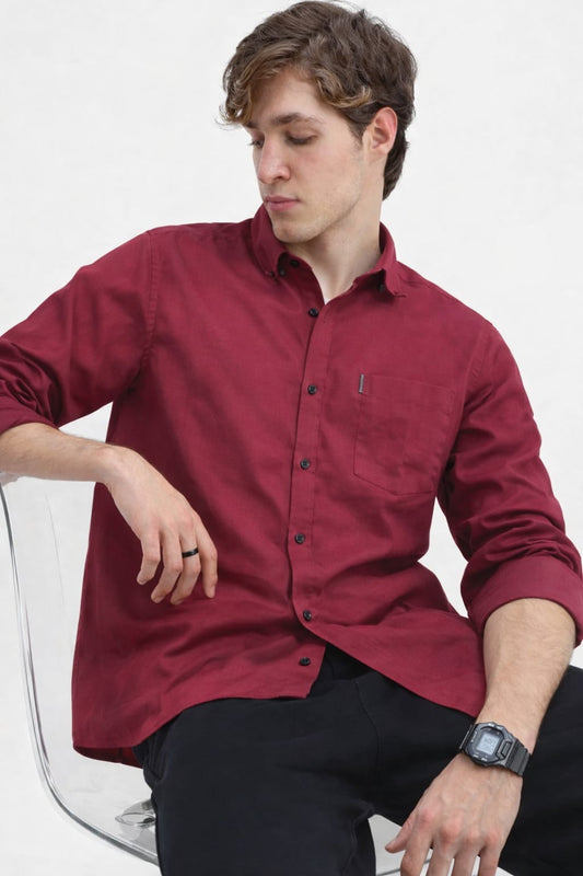 Man wearing a red button-up shirt sitting on a white chair.
