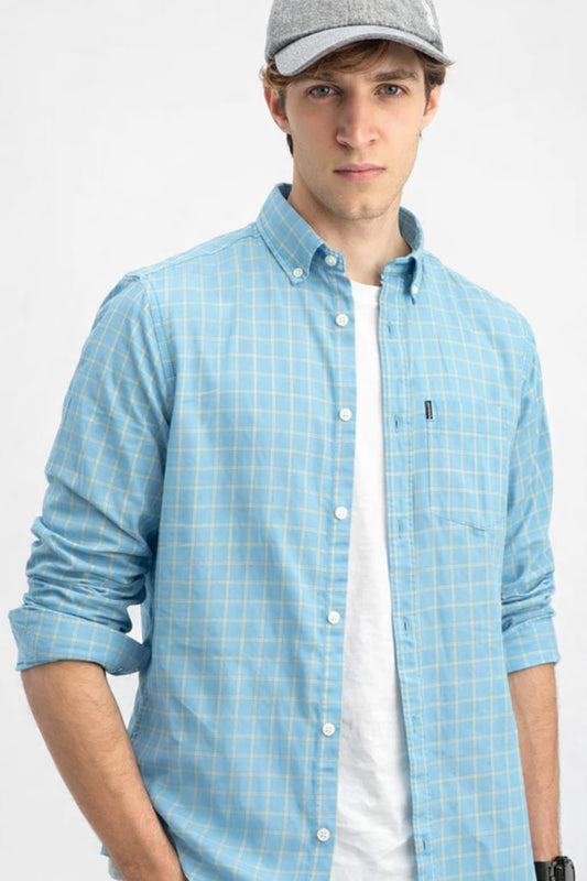 Man wearing a light blue checkered shirt over a white shirt with a gray cap on a white background