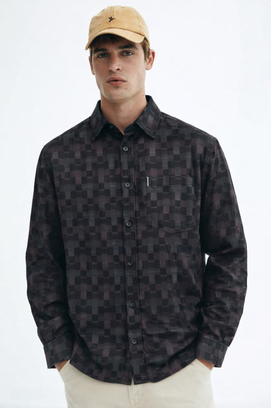 Man wearing a patterned shirt and beige cap on a white background