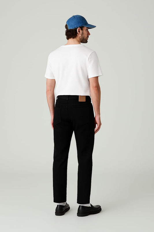 Man wearing a white t-shirt, black pants, and a blue cap on a light gray background