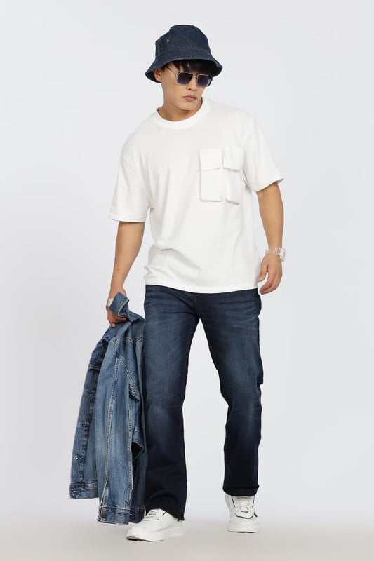 Person wearing a white t-shirt, blue jeans, and a navy bucket hat on a plain background