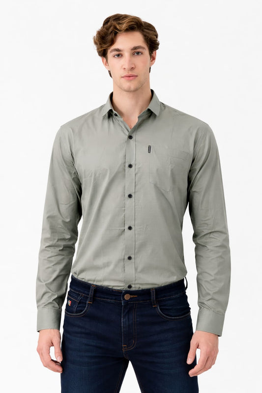 Man wearing a light gray button-up shirt and dark jeans on a white background