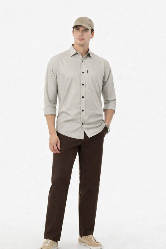 Man wearing a light gray button-up shirt and brown pants on a white background