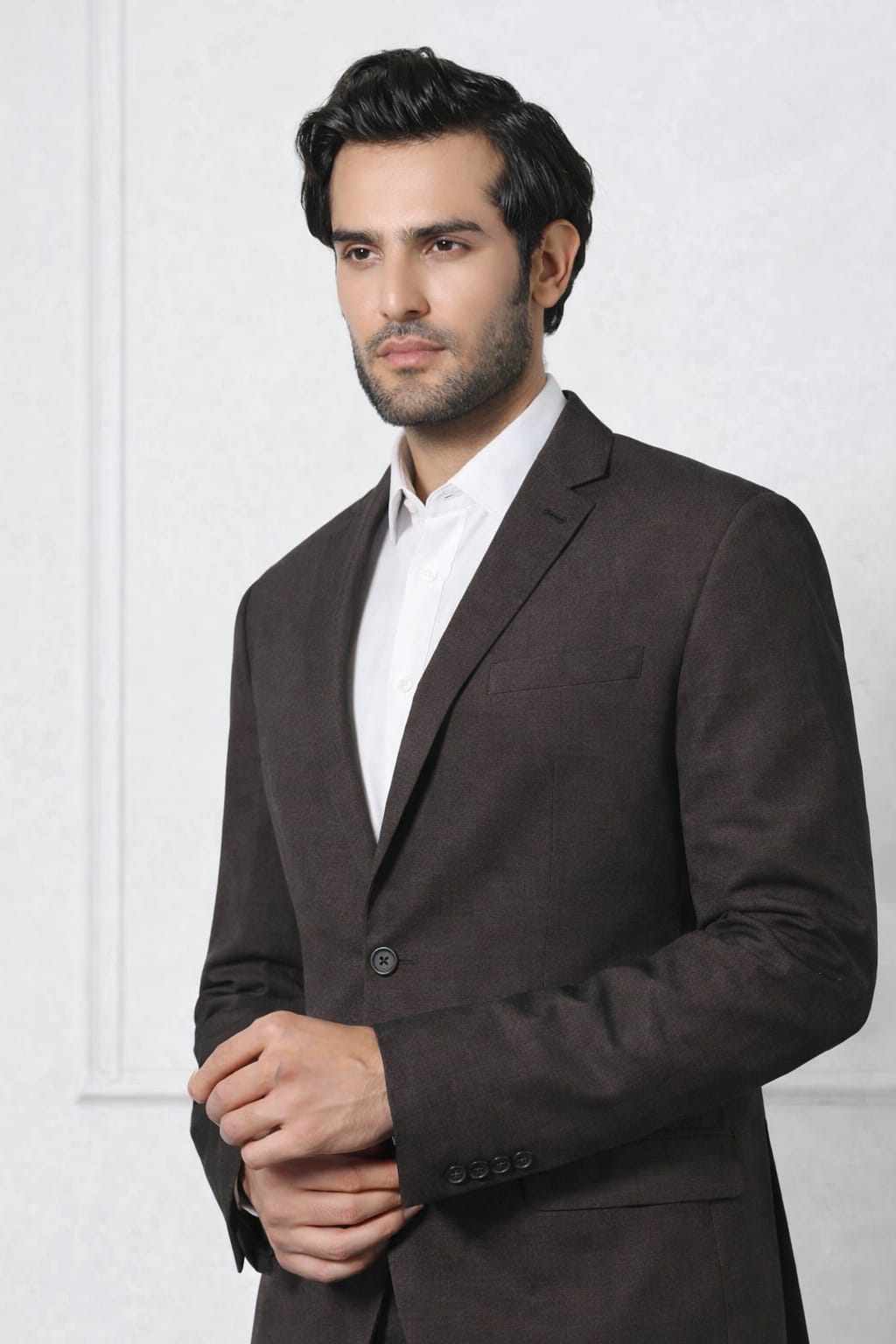 Man wearing a dark suit and white shirt against a white background