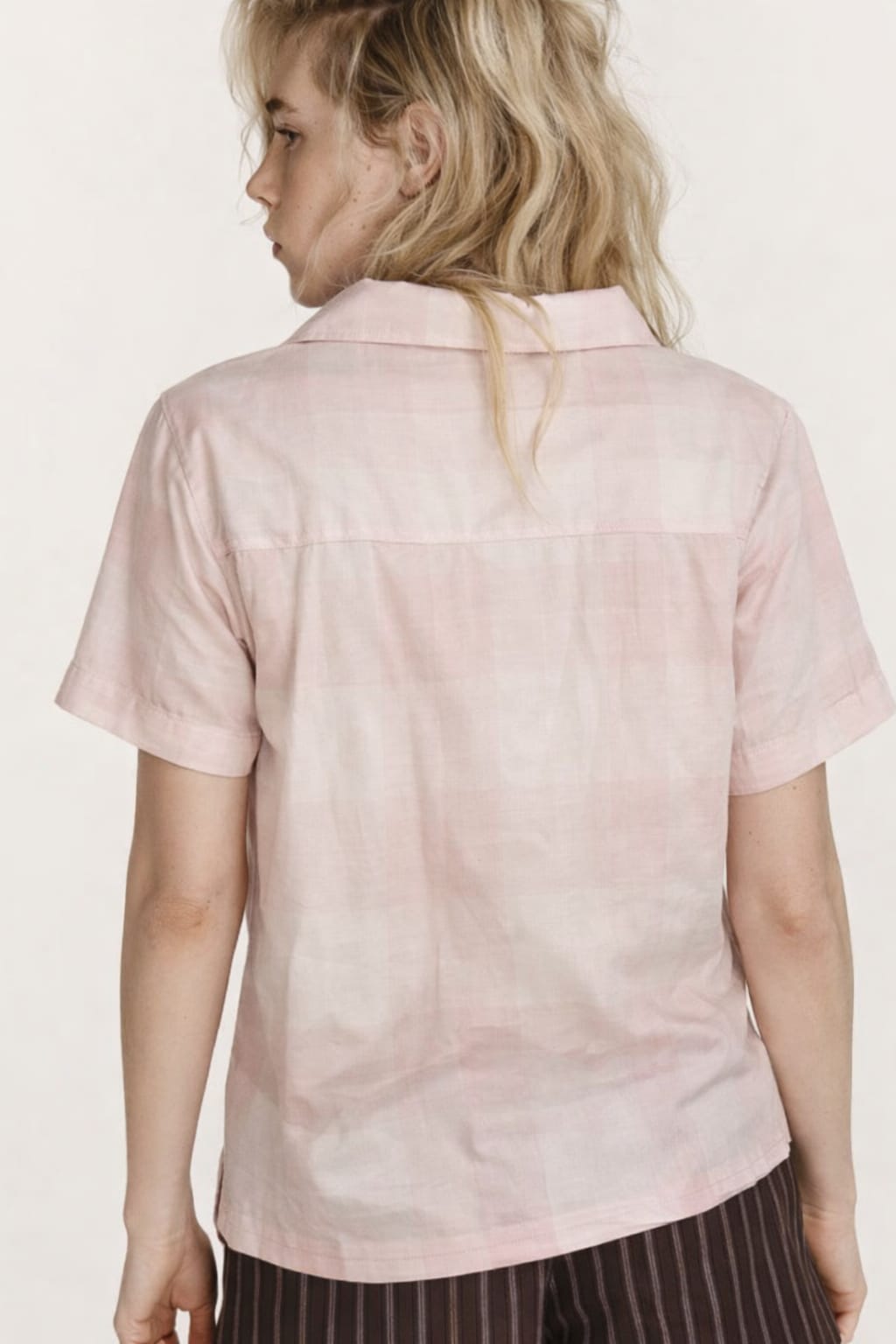 Person wearing a light pink shirt with a neutral background