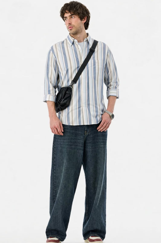 Man wearing a striped shirt and jeans with a black bag over his shoulder on a white background