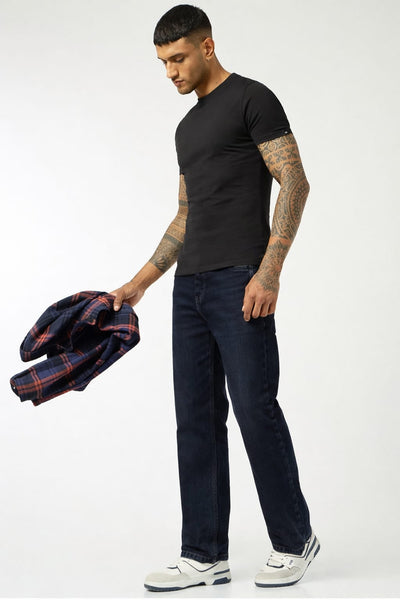 Man holding a plaid jacket, wearing a black t-shirt and dark jeans, on a white background