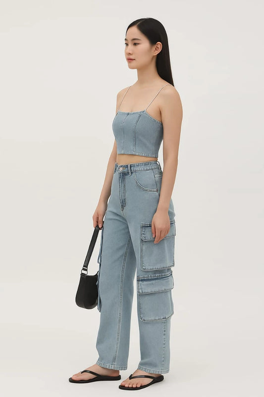 Woman wearing a light blue strap top and cargo pants holding a black bag on a white background
