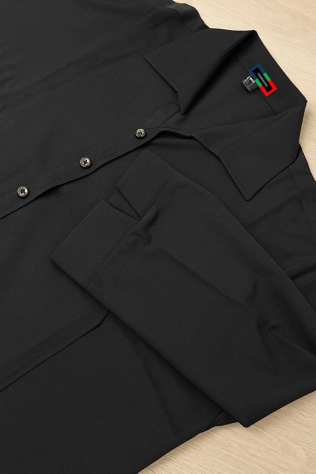 Black shirt with a brand logo on a beige surface