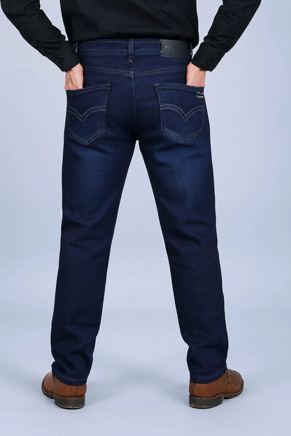 Person wearing dark blue jeans and brown shoes on a light gray background