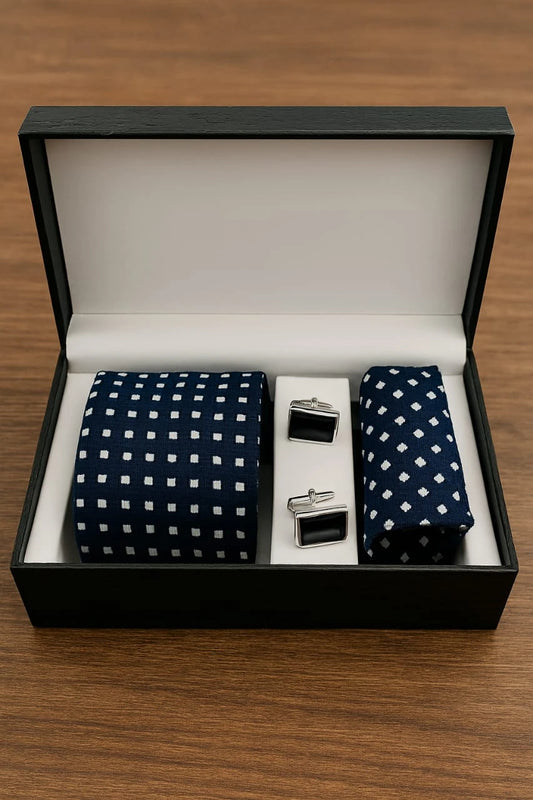 Navy blue tie with white polka dots and matching pocket square in a black box on a wooden surface.