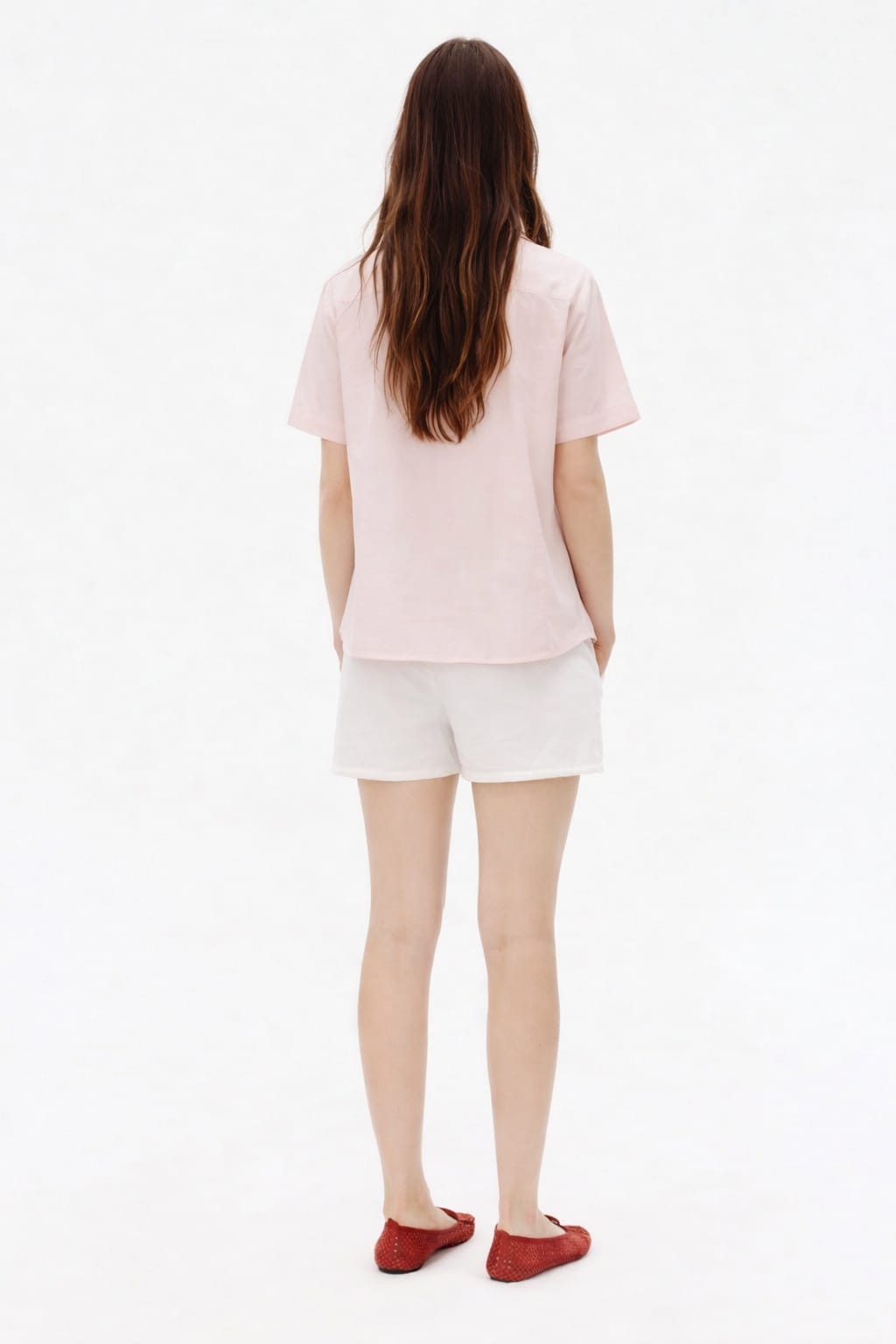 Person wearing a light pink t-shirt and white shorts on a white background