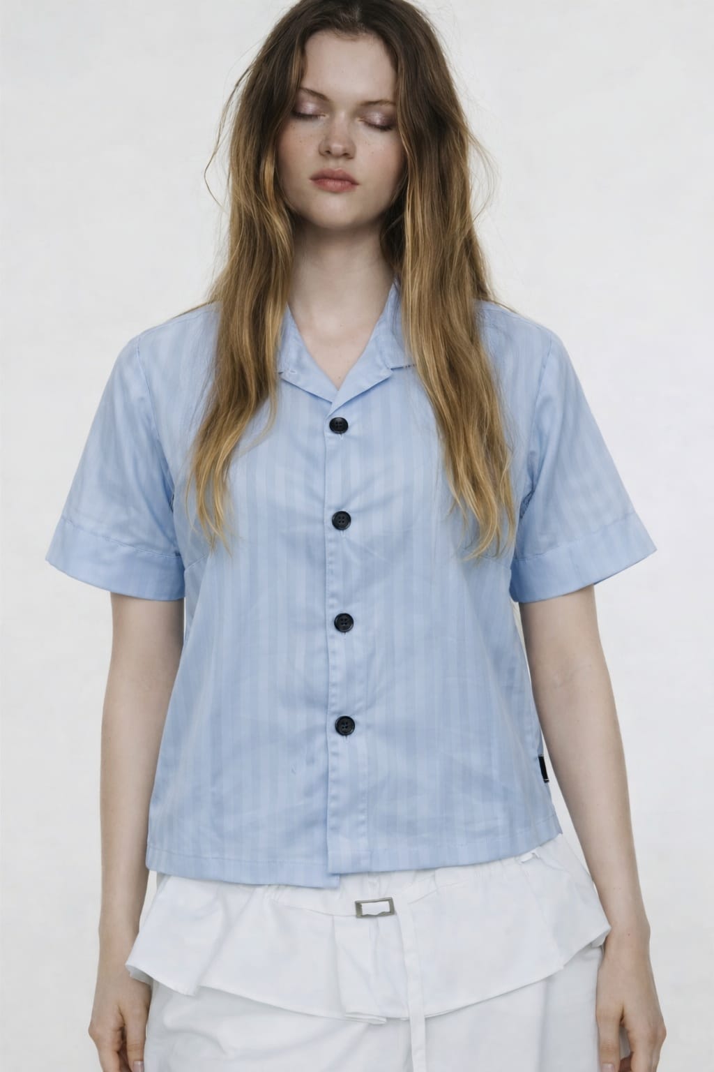 Woman wearing a light blue button-up shirt with a plain background