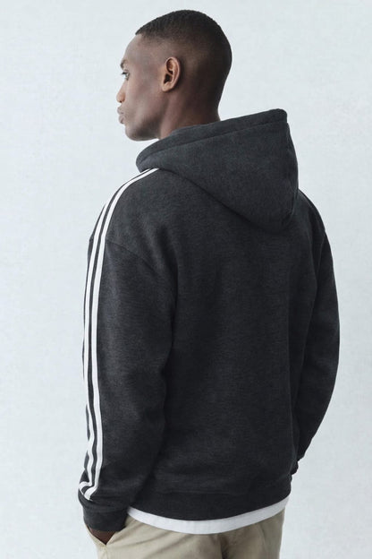 Person wearing a dark gray hoodie with white stripes on a light gray background