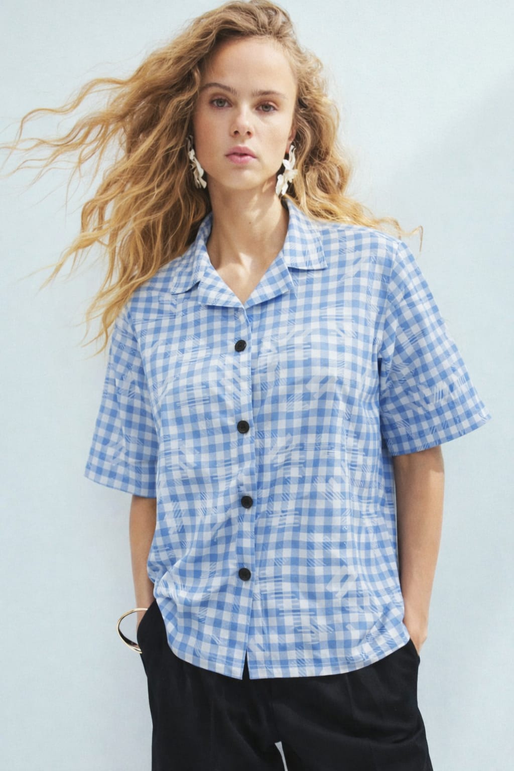 Woman wearing a blue and white checkered shirt against a light background