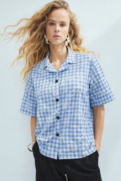 Woman wearing a blue and white checkered shirt against a light background