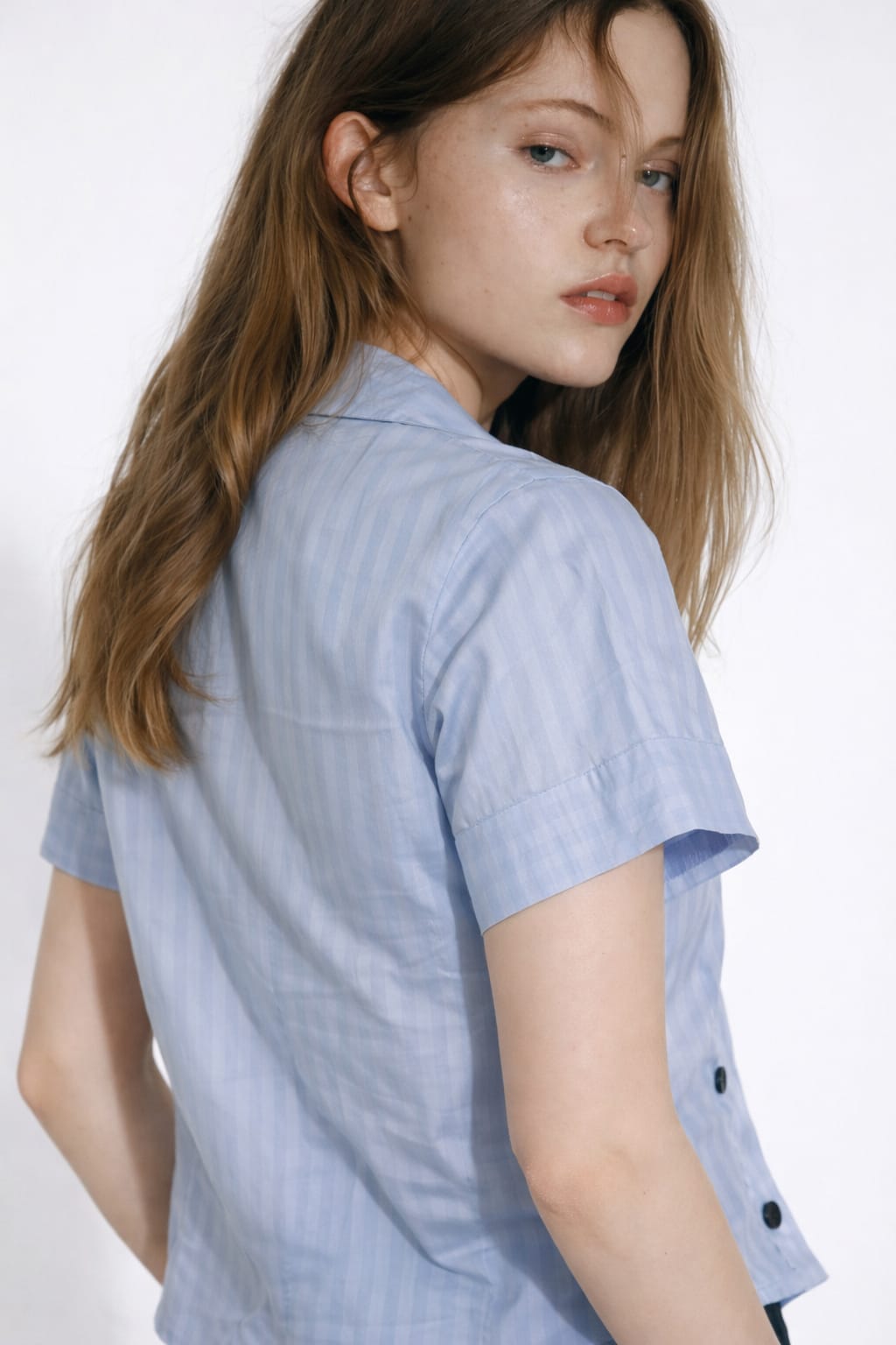 Woman wearing a light blue checkered shirt on a white background