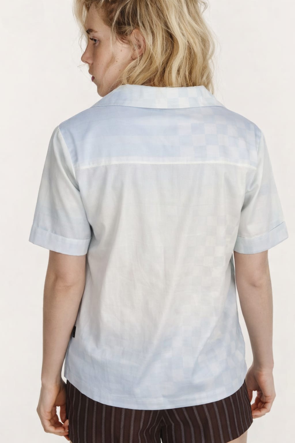 Person wearing a light blue and white gradient shirt with a plain background