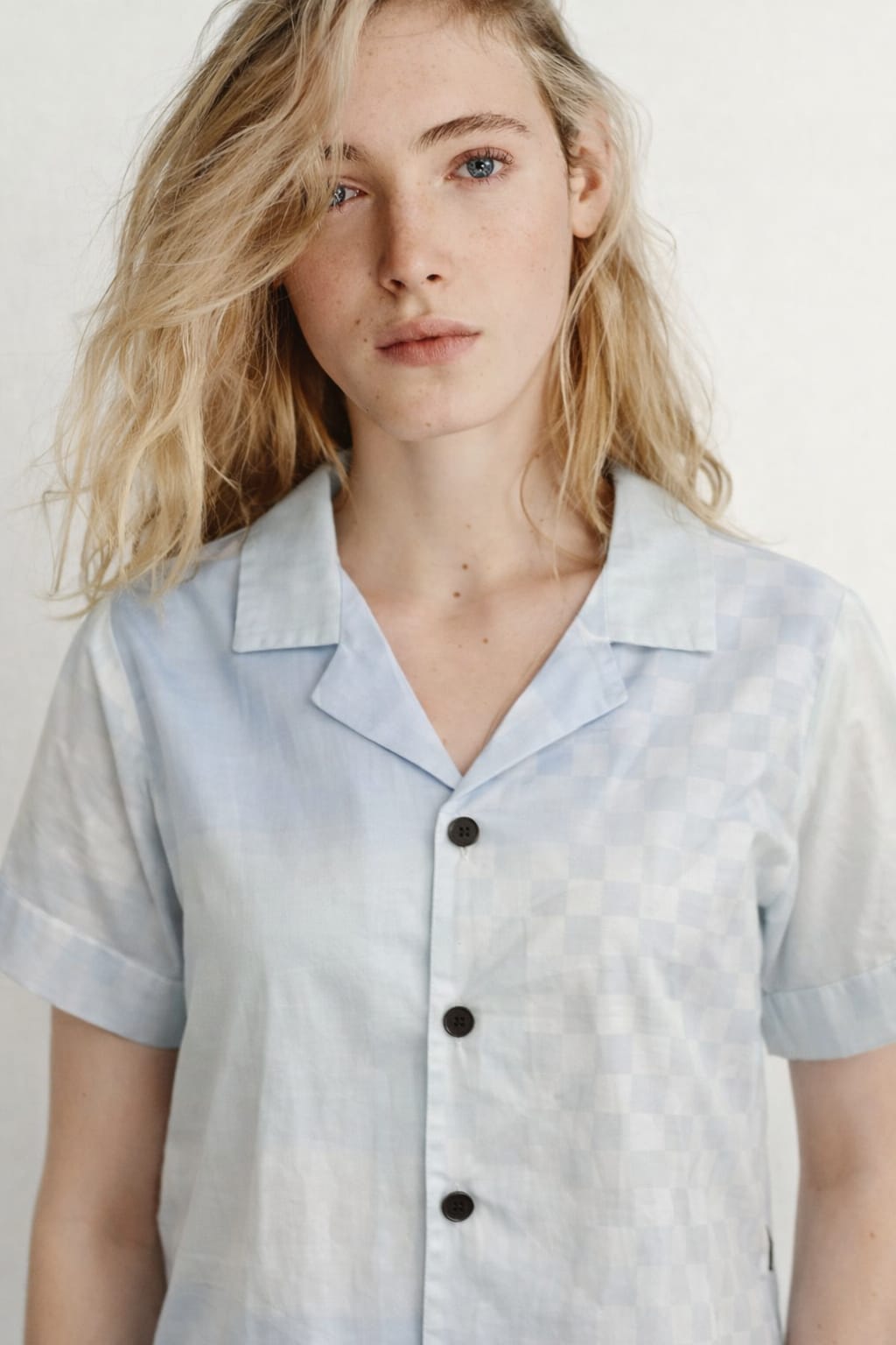 Woman wearing a light blue and white striped shirt against a plain background