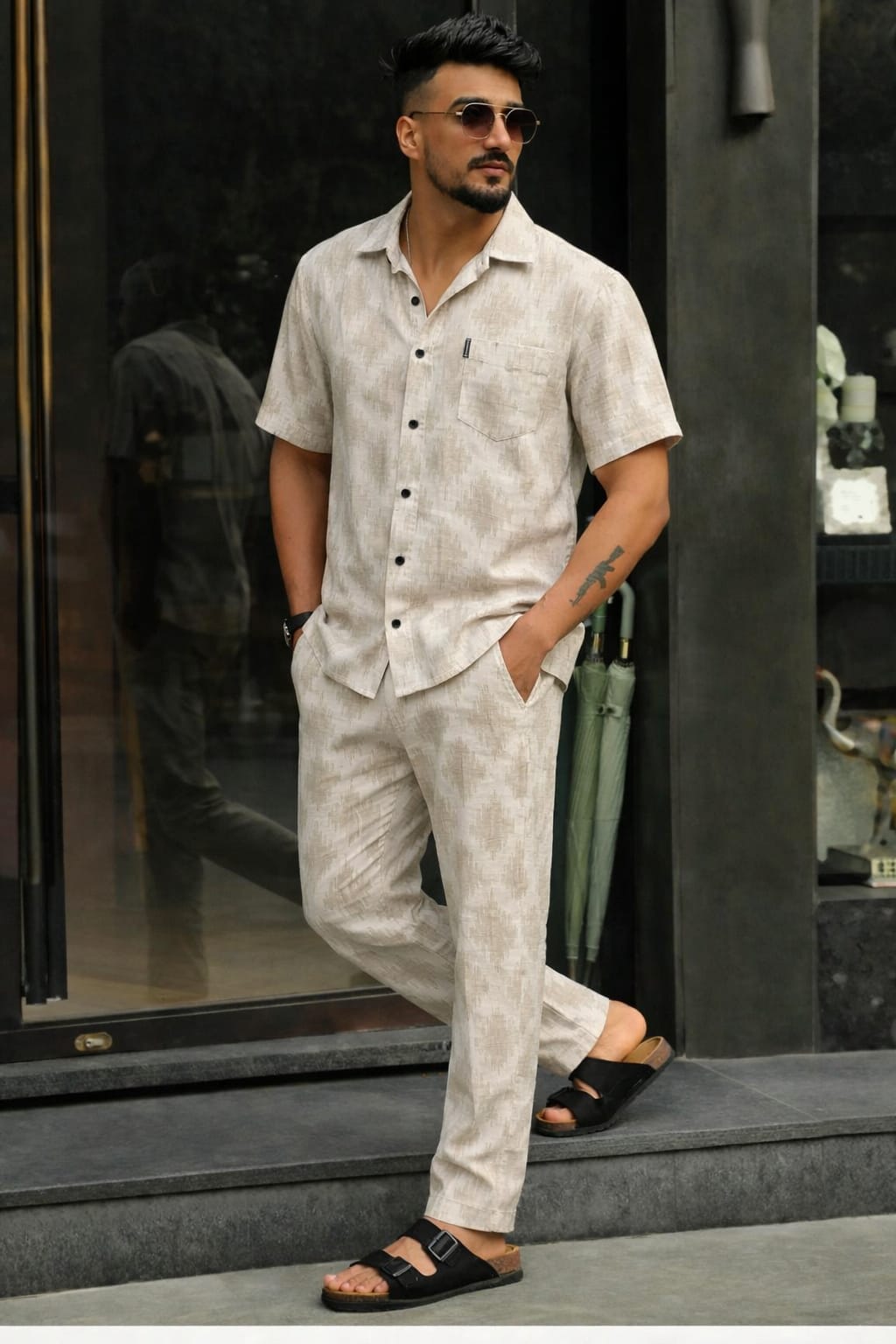 Man wearing a light-colored shirt and pants standing in front of a store entrance.