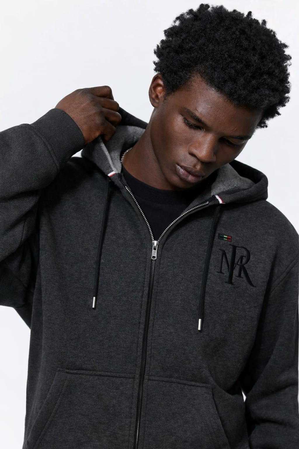 Person wearing a dark gray hoodie with a logo on a white background