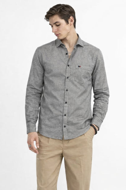 Man wearing a gray button-up shirt and beige pants on a white background