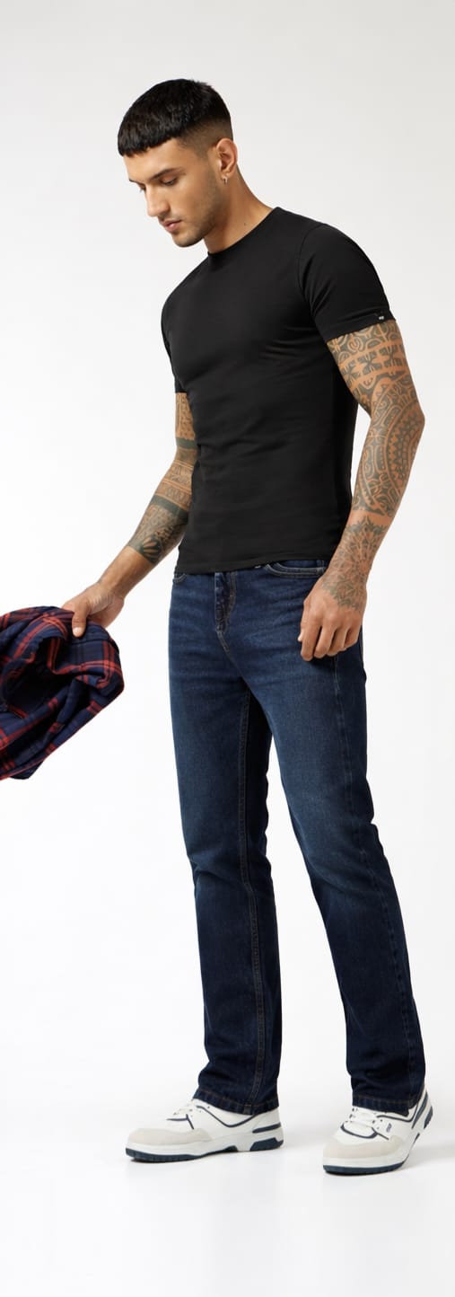 Man wearing a black t-shirt, blue jeans, and white sneakers on a white background
