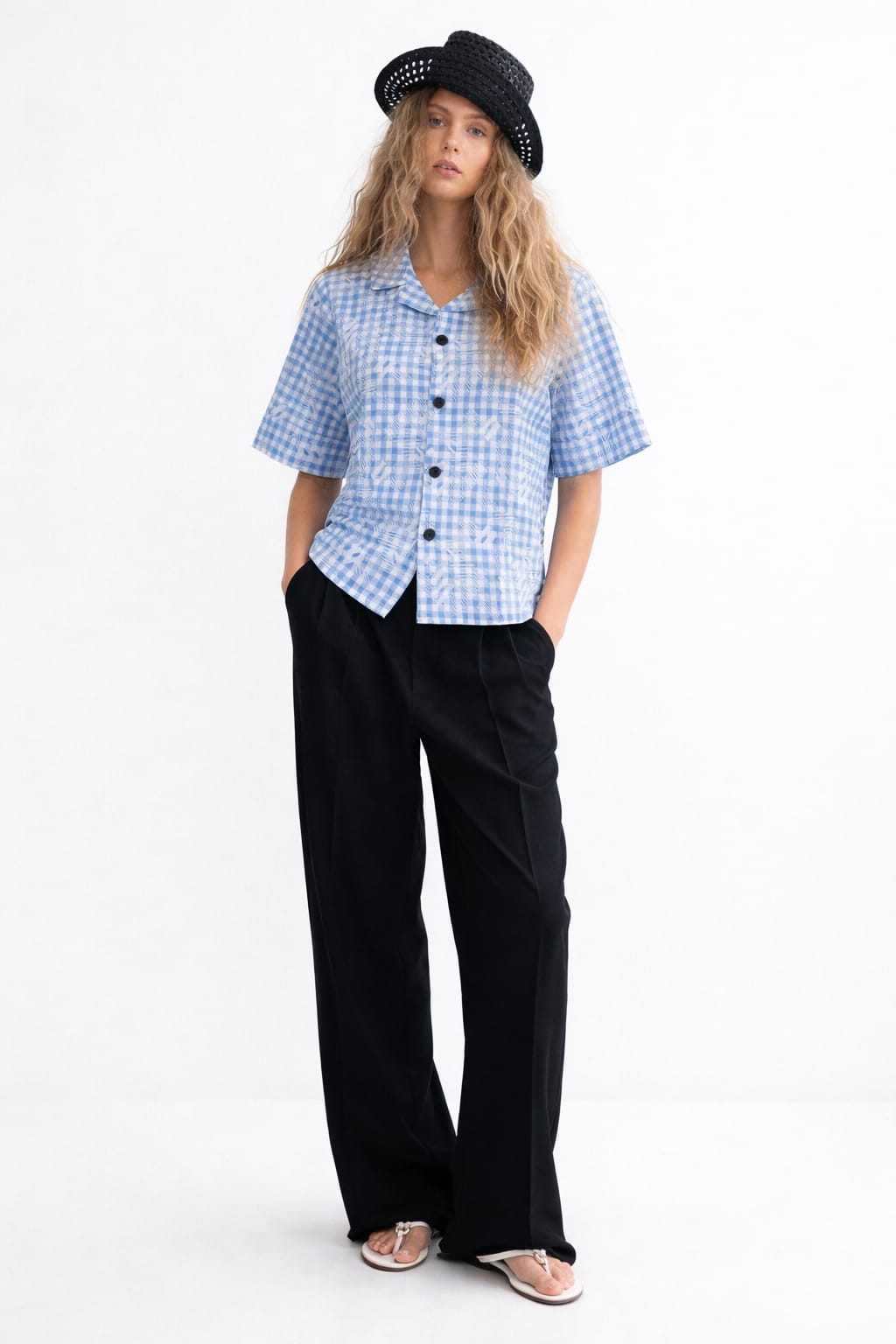 Woman wearing a blue checkered shirt and black pants on a white background