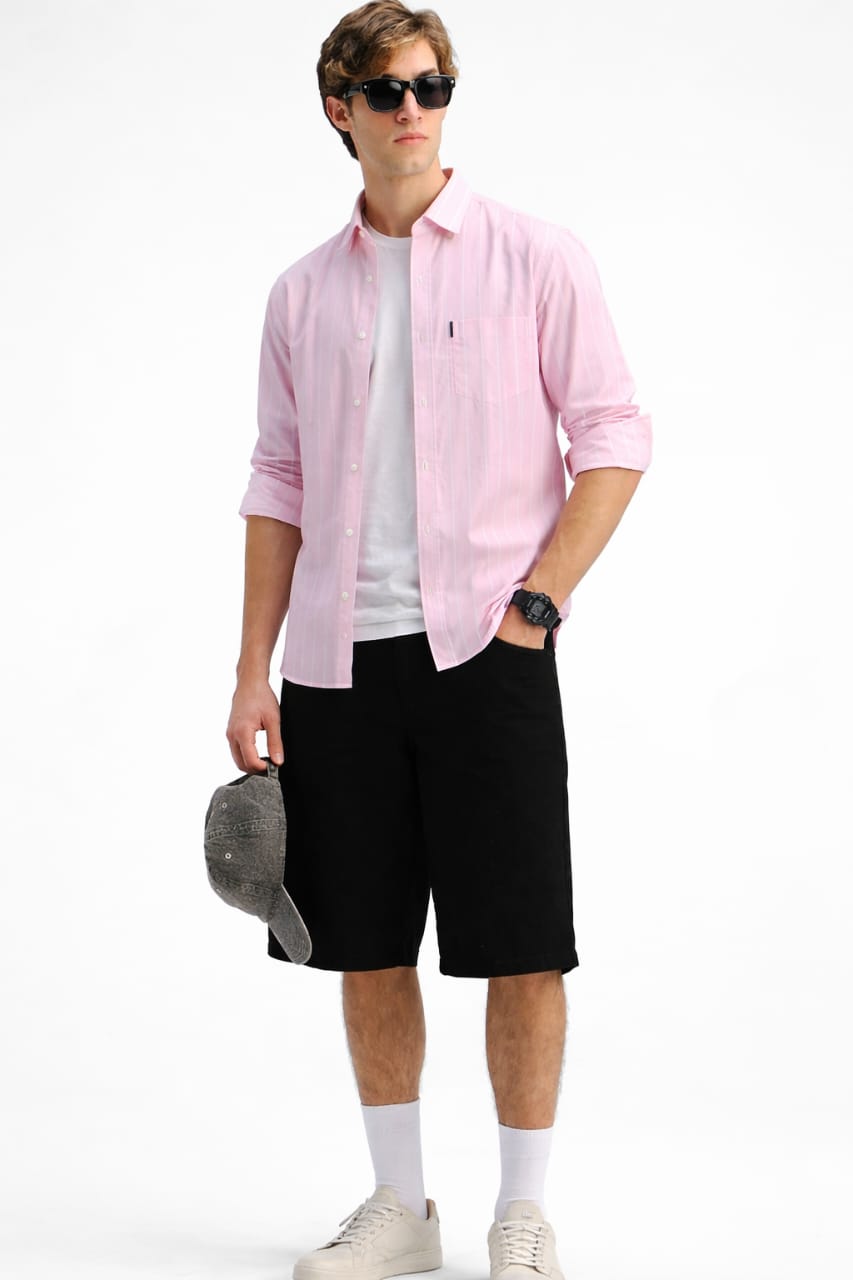 Man wearing a pink shirt, white t-shirt, black shorts, and sunglasses on a white background