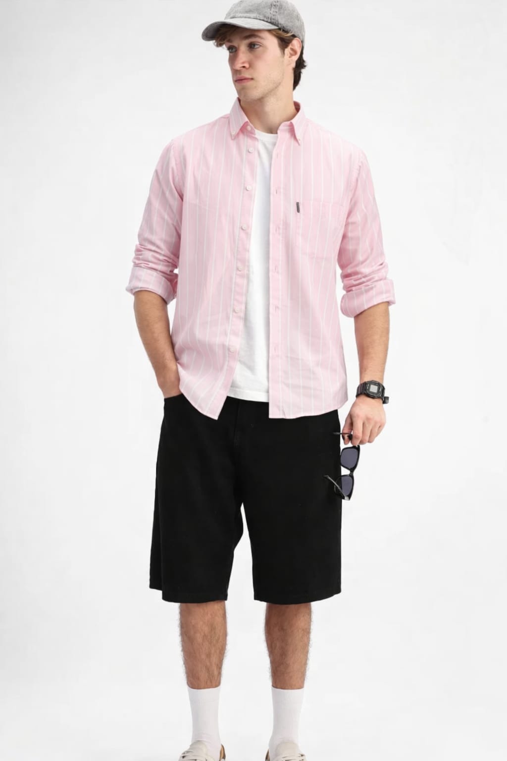 Man wearing a pink shirt, black shorts, and a cap on a white background
