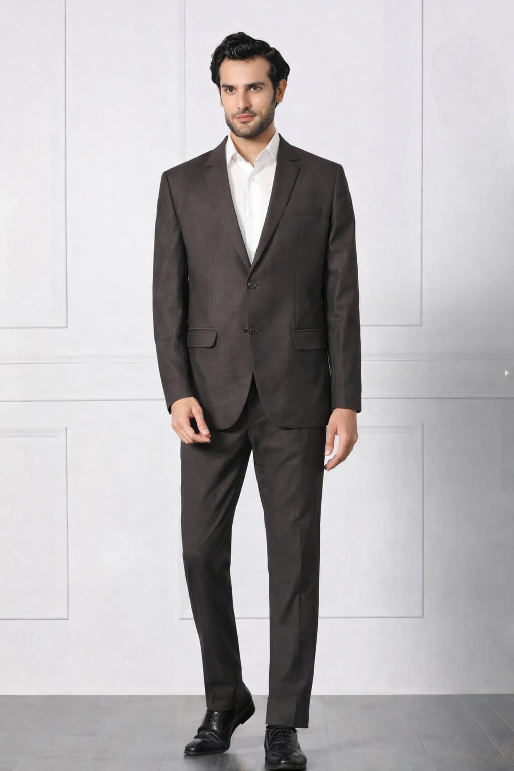 Man wearing a dark brown suit with a white shirt against a light gray background