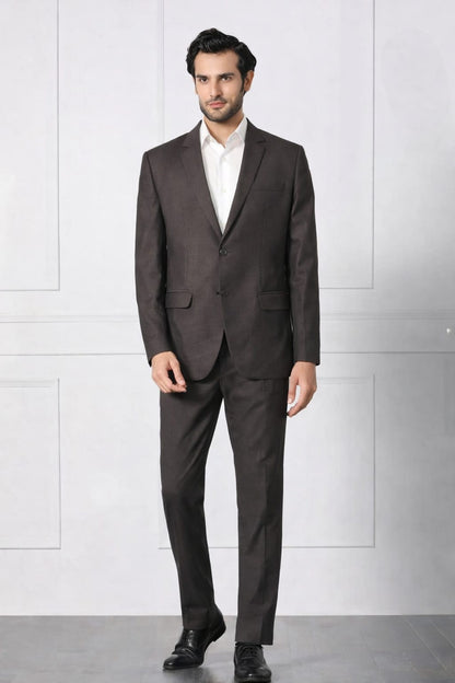 Man wearing a dark brown suit with a white shirt against a light gray background
