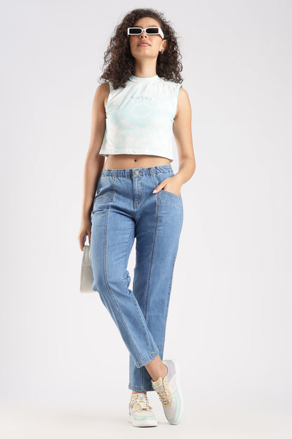 Woman wearing a white sleeveless top and light blue jeans on a white background