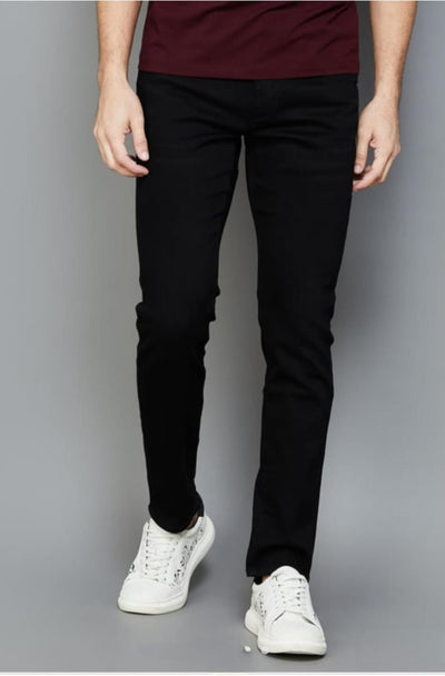 Person wearing black pants and white sneakers on a gray background