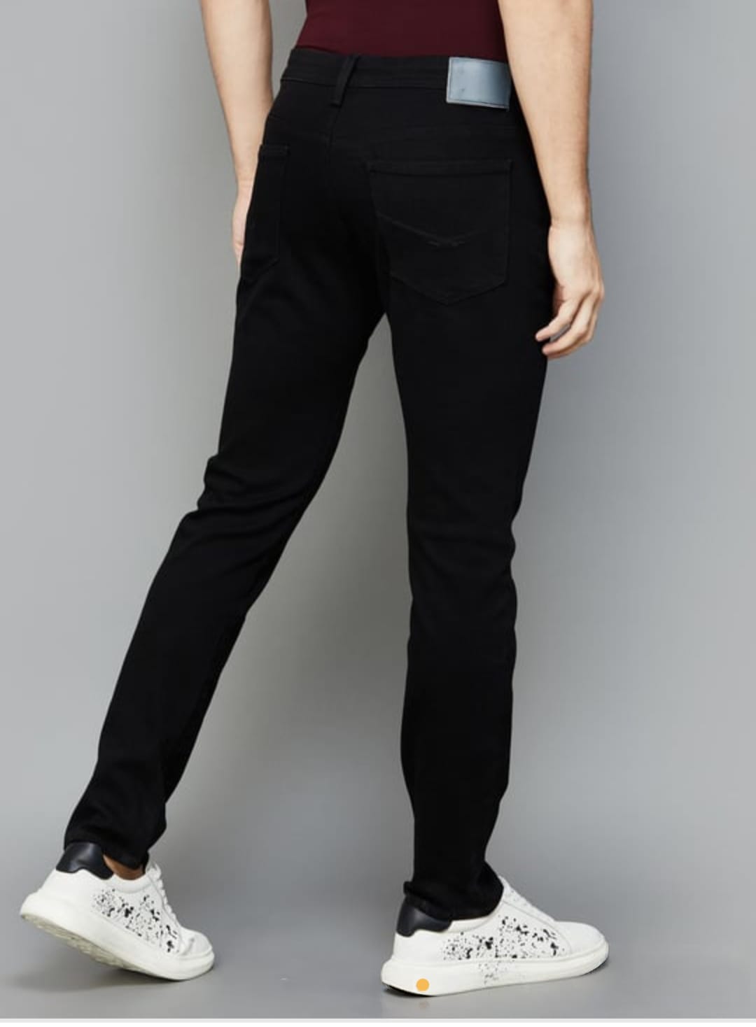 Person wearing black pants and white sneakers on a gray background