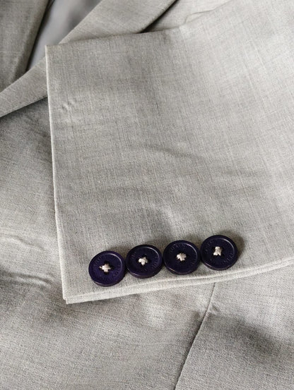 Close-up of a gray fabric with four dark buttons on a matching gray background
