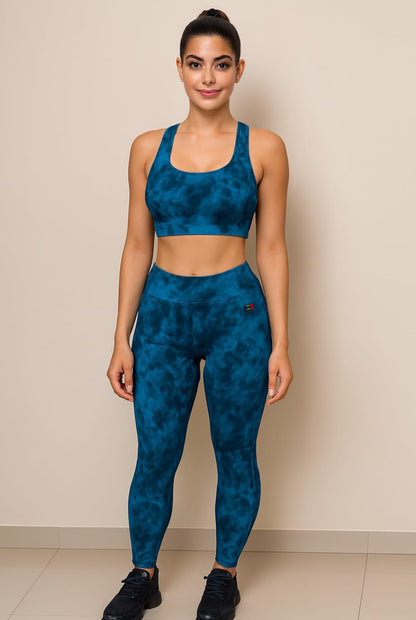 Woman wearing a blue patterned sports bra and leggings set against a beige background
