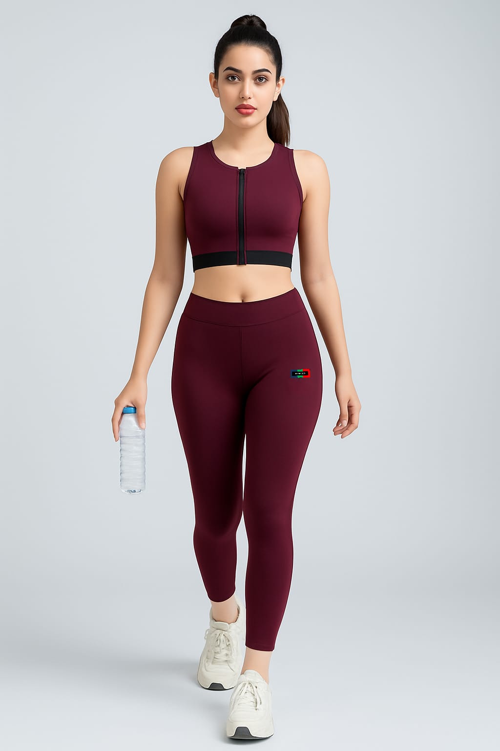 Woman wearing a maroon athletic outfit with leggings and sports bra on a gray background