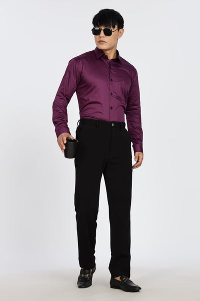 Man wearing a purple shirt and black pants holding a black mug on a white background