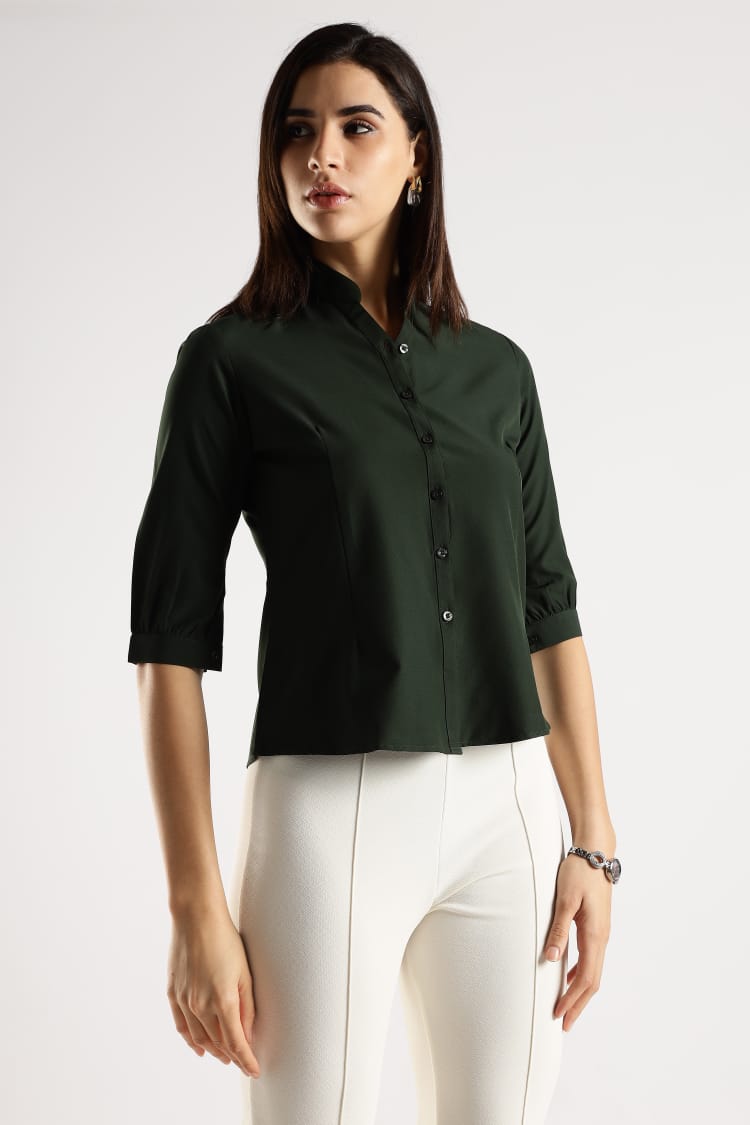 Woman wearing a dark green shirt and white pants on a white background