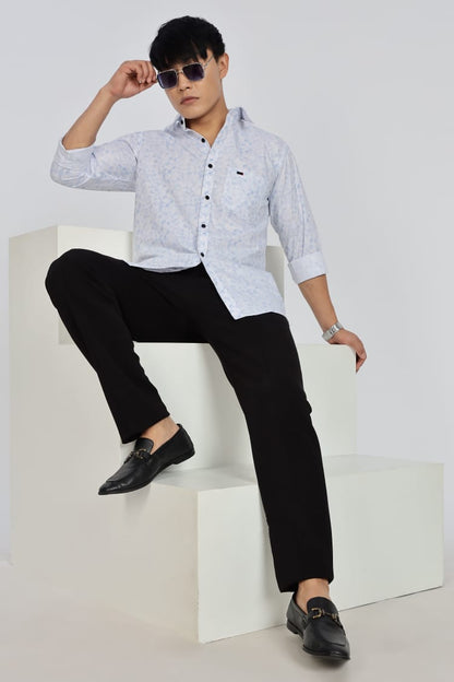 Man wearing a white patterned shirt and black pants on a white background