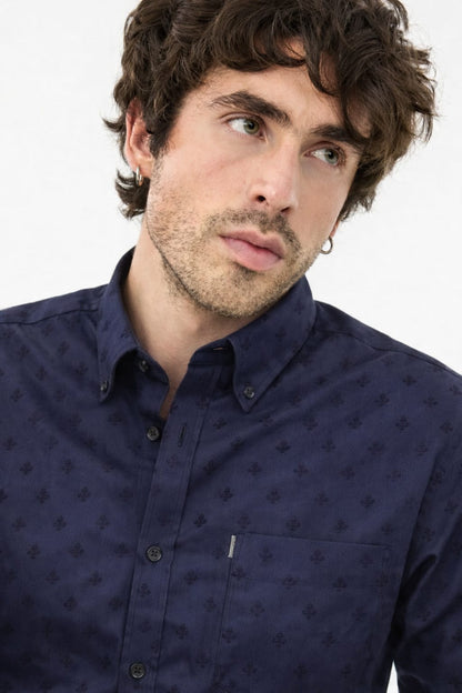 Man wearing a navy blue patterned shirt against a white background
