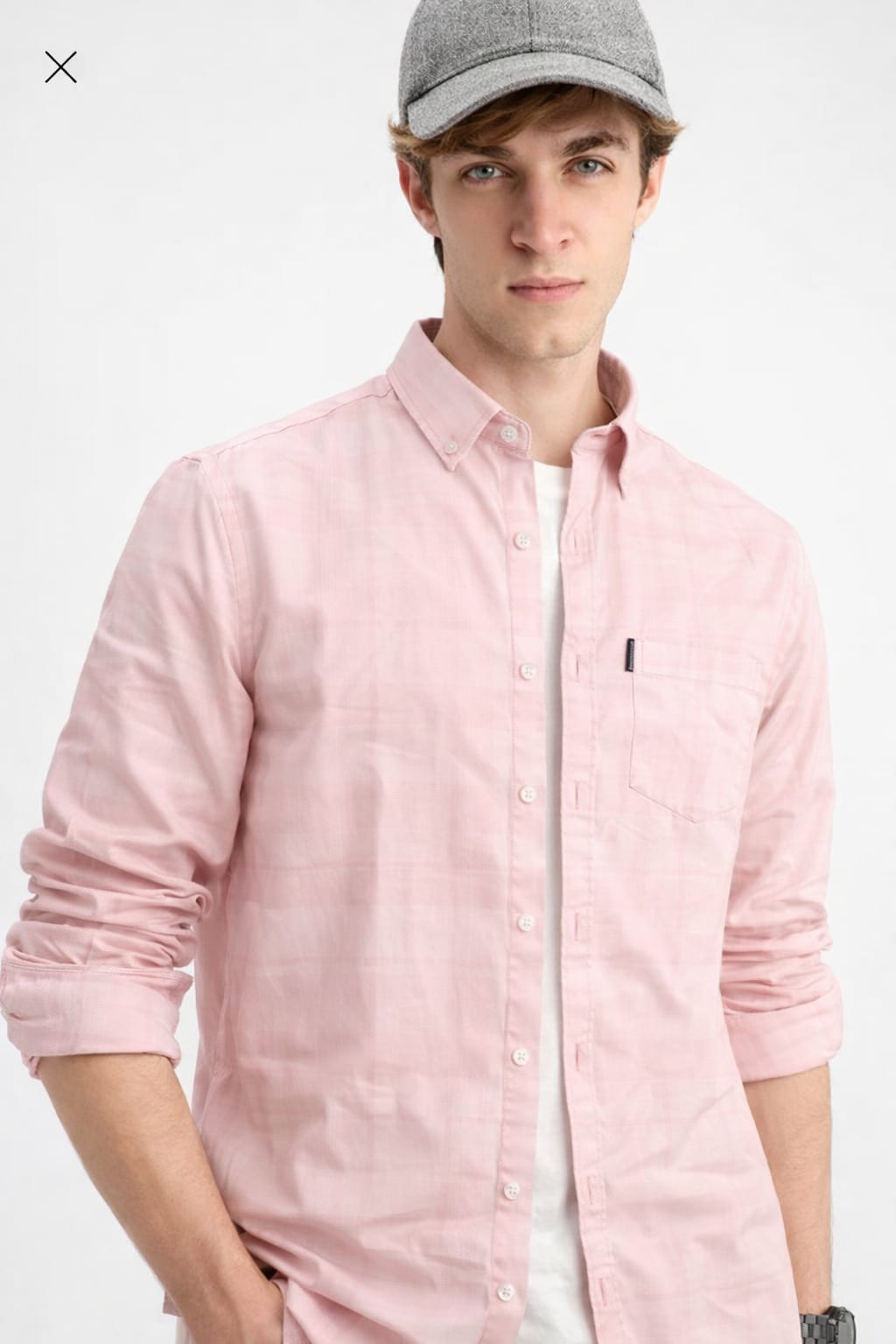 Person wearing a light pink button-up shirt with a small logo on a white background