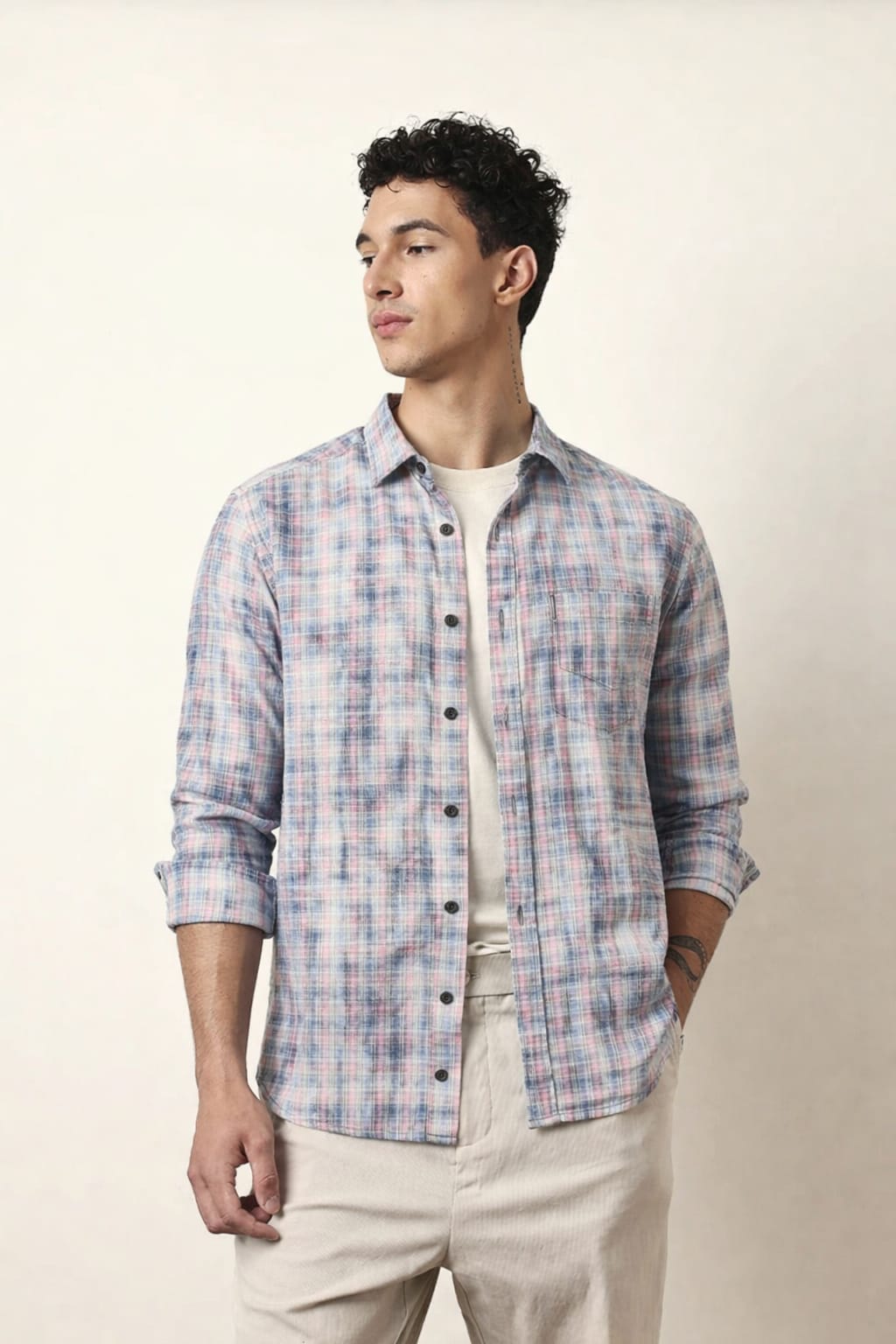 Man wearing a plaid shirt and beige pants against a plain background