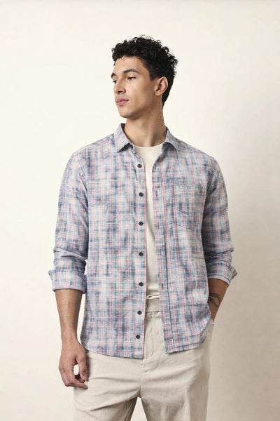 Man wearing a plaid shirt and beige pants against a plain background