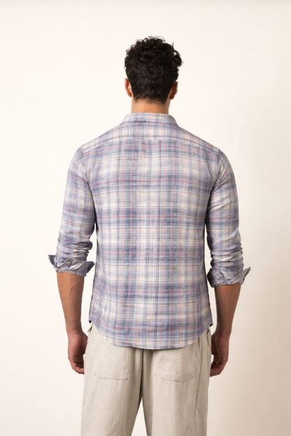 Man wearing a plaid shirt and light pants against a white background