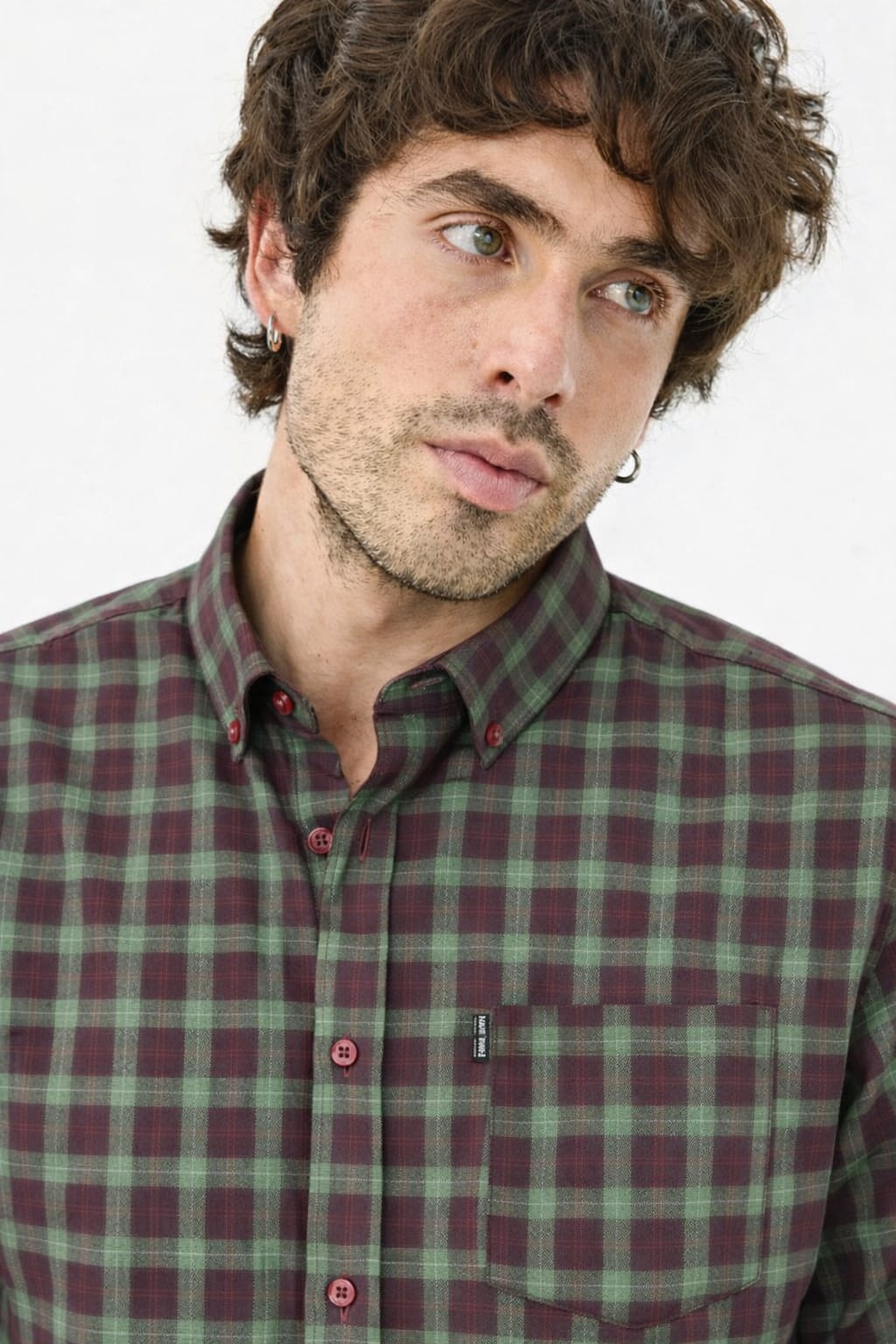 Man wearing a green and red plaid shirt against a white background